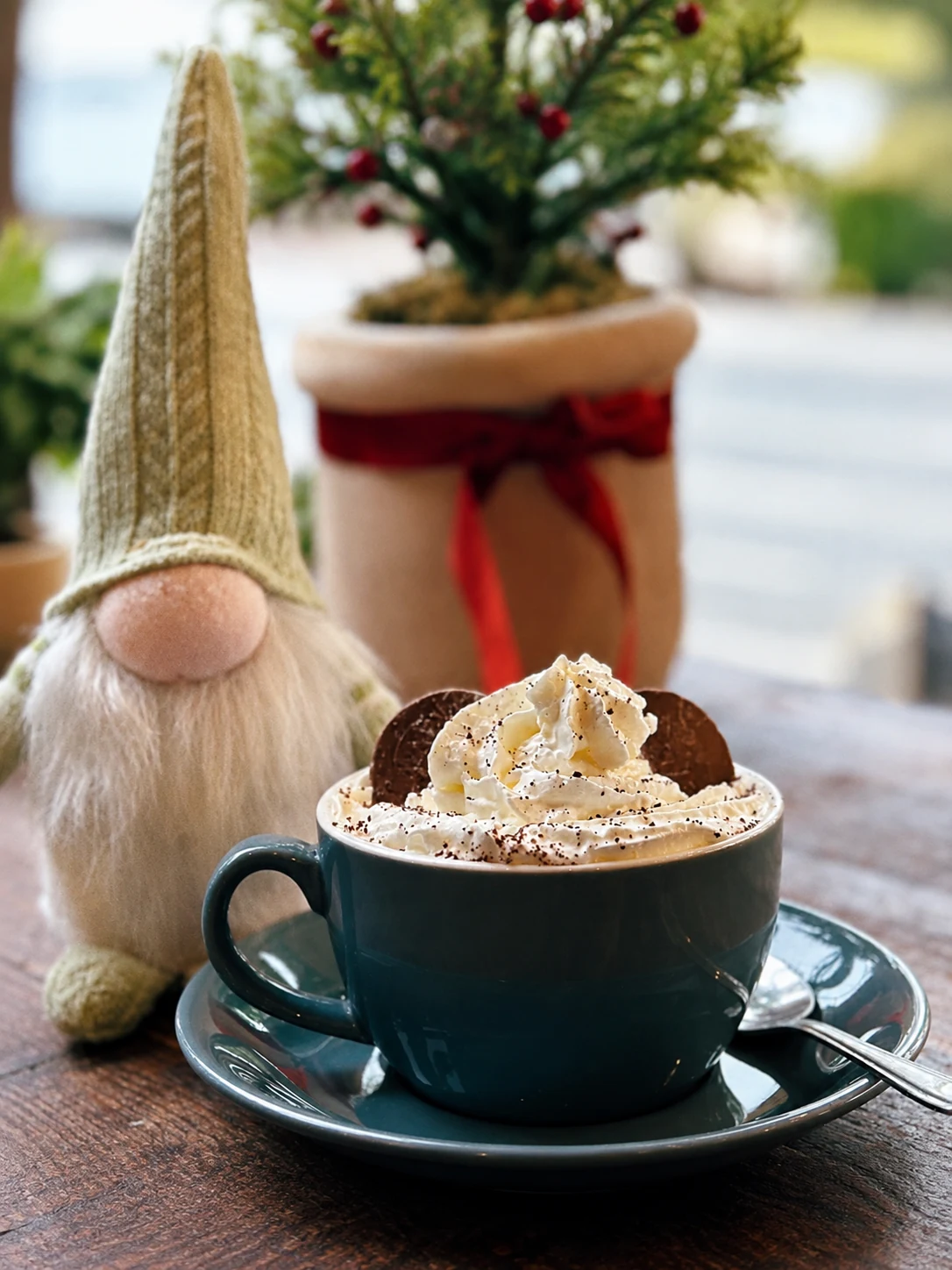 A hot chocolate with whipped cream beside festive decorations