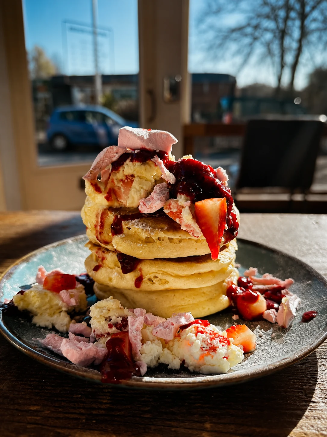 Pancakes topped with strawberries, cream and berry sauce